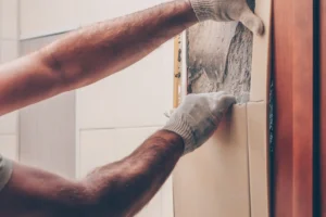 someone removing tile to reveal asbestos