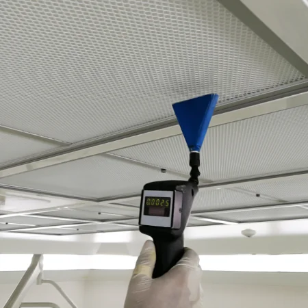 An indoor air quality technician testing ventilation performance of a ceiling vent.